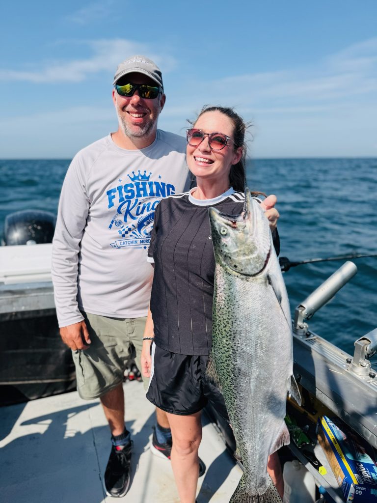 Pêcheuse souriante tenant une truite arc-en-ciel à bord du bateau, par une belle journée ensoleillée