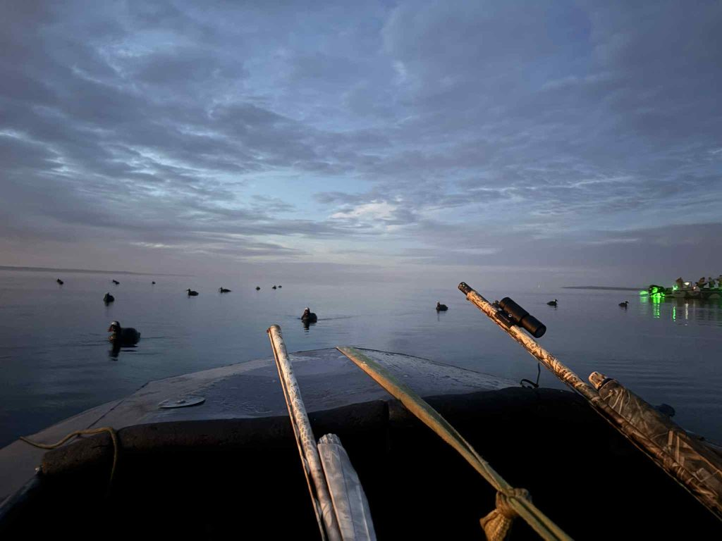 Vue depuis le bateau au lever du jour, avec les appelants disposés sur l’eau calme