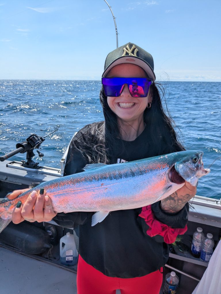 Pêcheuse souriante tenant une truite arc-en-ciel colorée à bord du bateau