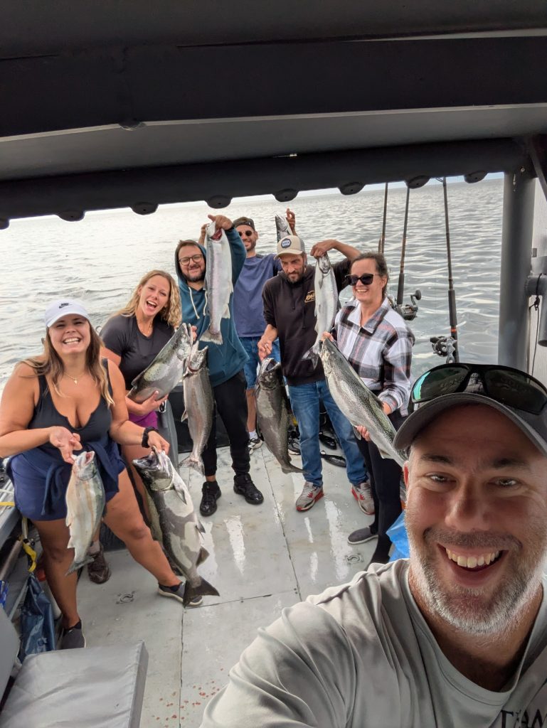Selfie de groupe à bord du bateau, les pêcheurs brandissant leurs saumons